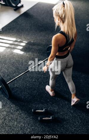 Starke Fitness Frau, in Sportbekleidung, trainiert mit schweren Gewichten im Fitnessstudio, Sportswoman hebt die Langhantel im Fitnessstudio. Stockfoto