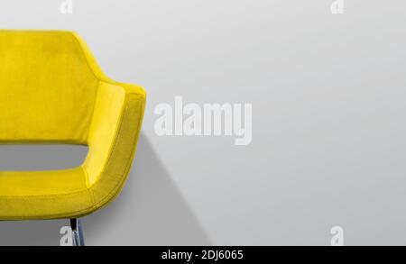 Gelber Stuhl vor einer grauen Wand. Selektiver Fokus. Stockfoto