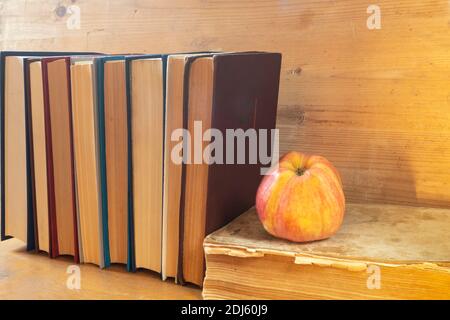 Der Rote Apfel mit dem Buch ruht nach dem hölzernen Regiment. Nahaufnahme der Motive. Stockfoto
