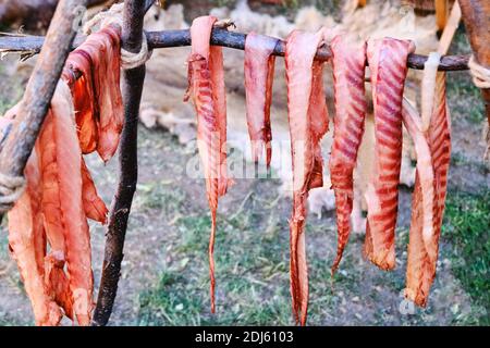 Kochen Speck auf Feuer. In Streifen geschnittenes Fleisch wird auf Feuer gegart aufgereiht. Das Leben im Lager der ersten amerikanischen Siedler im wilden Westen und Gold gedeihen Stockfoto