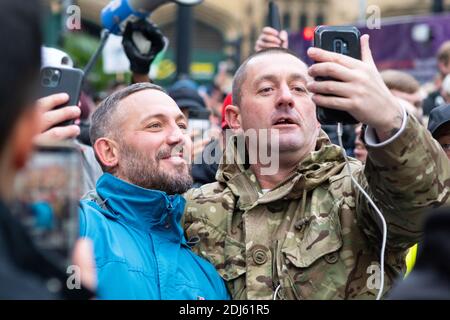 Manchester Sa 12. Dezember 2020. Freiheitsdemonstration/Anti-COVID-19-Beschränkungen Protest. Zwei Demonstranten halten an, um sich zu umarmen, während sie das Ereignis live übertragen Stockfoto