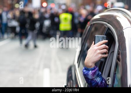 Manchester Sa 12. Dezember 2020. Freiheitsdemonstration/Anti-COVID-19-Beschränkungen Protest. Der Fahrer eines Autos hält das Smartphone aus dem Fenster, als sich der Protest nähert Stockfoto