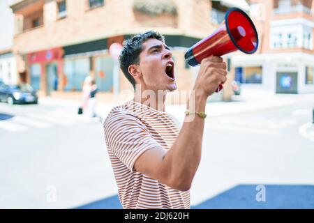 Junger hübscher kaukasischer Mann, der mit Megaphon in der Stadt schreit Stockfoto