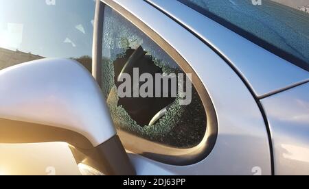 Der Einbrecher brach die Seitenscheibe des Wagens, um zu stehlen. Ein Beispiel für eine Versicherung gegen Raub. Stockfoto