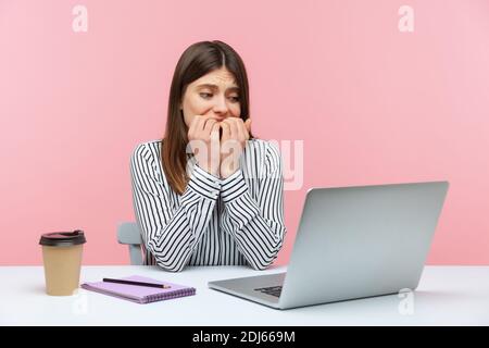 Ängstliche Frau Büroangestellte beißen ihre Nägel sitzen am Arbeitsplatz und Blick auf Laptop-Bildschirm mit nervösen Sorgen Ausdruck, Angst vor Software-Fehler Stockfoto
