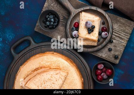 Traditionelle Pfannkuchen in einem Stapel und separat serviert auf einem dunkelblauen Hintergrund. Stockfoto