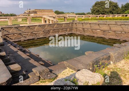 Hampi, Karnataka, Indien - 4. November 2013: Königliche Einschließung. Abgestufte Tank in seiner grünen Umgebung in braunem Stein gebaut gesetzt. Mahanavami Dibba oder die D Stockfoto