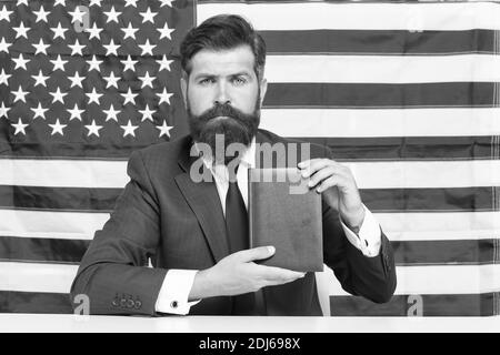 Freiheit des Druckens. Patriotischer Geschäftsmann halten Buch auf amerikanischer Flagge Schwarzboden. Amerikanische Freiheit. Tag der Unabhängigkeit. Juli. Stolz und Freiheit. Politische Rechte und Freiheiten. Freiheit der Wahl. Stockfoto