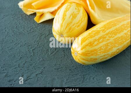 Gelbe Zucchini auf grauem Hintergrund in den Farben des Jahres 2021 - leuchtend gelb und ultimativ grau. Stockfoto