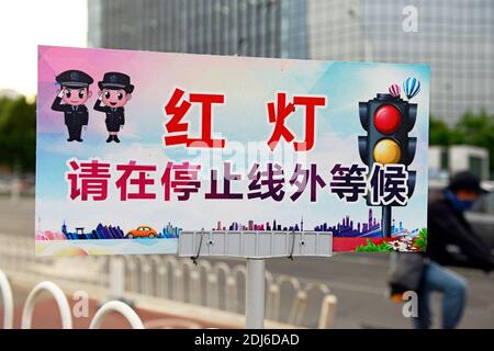 A Bitte halten Sie an und warten Sie außerhalb der Linie, wenn rote Ampel zeigt' Zeichen auf einer Straße in Peking, China Stockfoto