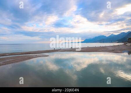 Fischer zu Fuß am Strand von Antalya Taurus Berge und Rosa lila wolkigen Himmel im Hintergrund Stockfoto