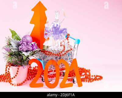 Roter Weihnachtsbaum und die Inschrift 2021 im Warenkorb. Weihnachtsbaumschmuck im Warenkorb auf rosa Hintergrund. Urlaubskonzept Stockfoto
