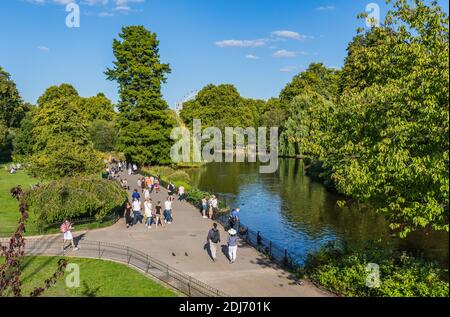 Anzeigen von Menschen zu Fuß im Sommer durch den See und die Gärten von St James's Park, Westminster, London, England, UK. St. James Park. Stockfoto