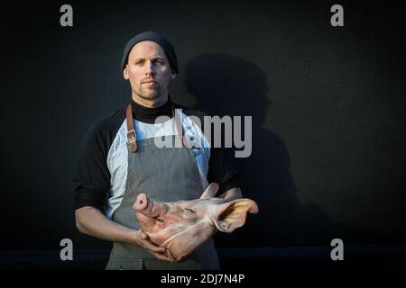 GROSSBRITANNIEN / England / Metzger hält einen Schweinkopf. Stockfoto