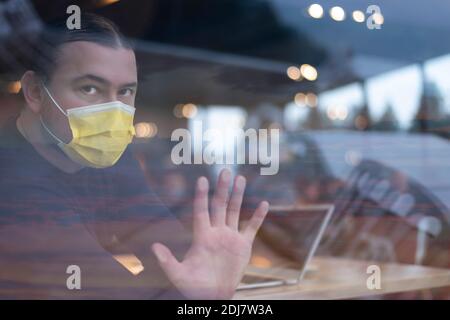 Covid-19 Situation im Geschäftskonzept. Geschäftsmann mit chirurgischer Maske. Arbeiten am Computer-Laptop. Gestresst aufgrund von Corona Virus. Blick weg zu Stockfoto