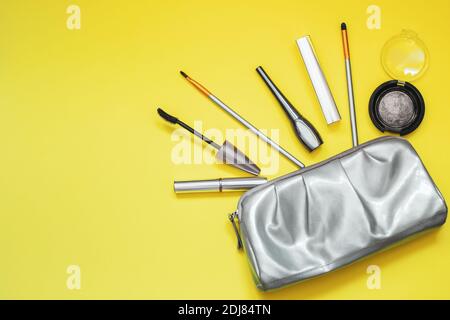 Graue glänzende Kosmetiktasche auf gelbem Hintergrund. Ort für Ihren Text. Trendfarben von 2021. Stockfoto