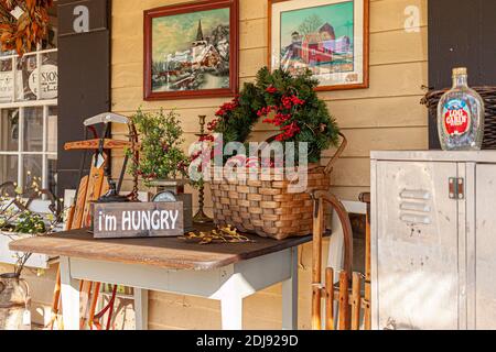 Clifton, VA, USA 11-14-2020: Eine Vintage-Porch-Dekoration mit einer leeren Getränkeflasche auf Metallschrank, einem Strohkorb, ein paar Wandaufhänger Farben, chris Stockfoto