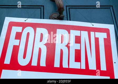 Ein großes for Rent-Schild (weißer Text auf rotem Hintergrund) ist am Metalltürgriff an der Eingangstür eines alten Stadthauses angebracht. Ein vielseitiges Bild für REA Stockfoto