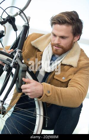 Nahaufnahme eines Mannes, der sein Fahrrad auf der Straße einsperrte Stockfoto