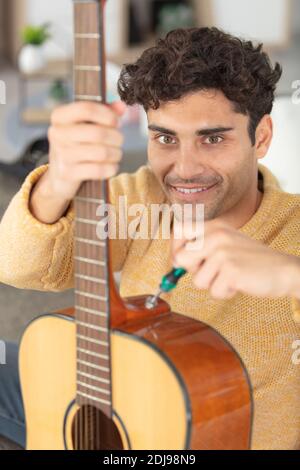 Junge gut aussehende Werkstatt Reparatur Gitarre Stockfoto