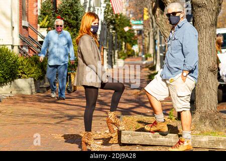 Alexandria, VA, USA 11-28-2020: Eine stylische junge rothaarige Frau und ihr Vater in lässiger Kleidung und Stiefeln reden draußen an einem sonnigen Tag. Sie Stockfoto