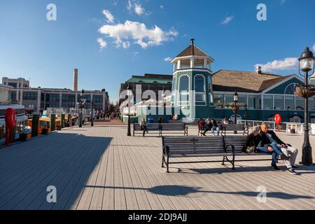 Alexandria, VA, USA 11-28-2020: Ein sonniger Tag am Ufer des alten Stadtteils von Alexandria mit Menschen sitzen auf Bänken auf dem Pier in FRO Stockfoto