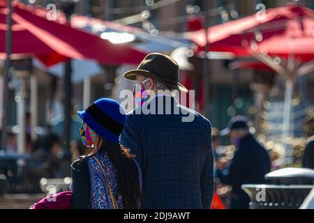 Alexandria, VA, USA, 11-28-2020: Ein älterer kaukasischer Mann mit Cowboyhut und Jacke läuft an einem sonnigen Tag mit seinem jüngeren W Stockfoto