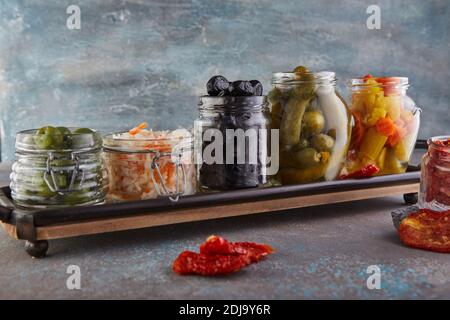 Fermentierte Dosen vegetarische Lebensmittel Konzept. Sauerkraut, eingelegte Karotten, eingelegte Gurken, eingelegte Oliven und Oliven, getrocknete Tomaten in Gläsern. Der Stockfoto