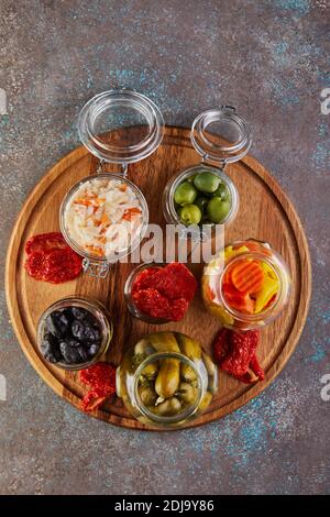 Fermentierte Dosen vegetarische Lebensmittel Konzept. Sauerkraut, eingelegte Karotten, eingelegte Gurken, eingelegte Oliven und Oliven, getrocknete Tomaten in Gläsern. Der Stockfoto