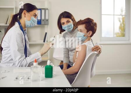 Erschrocken kleines Kind macht lustige Gesicht, wenn er Spritze sieht Nadel in der Hand der Krankenschwester Stockfoto