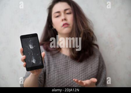 Das Mädchen mit Unzufriedenheit zeigt ihr zerbrochenes Gadget. Stockfoto