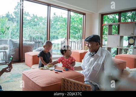 Porträt eines Großvaters mit seinem Enkel spielt in der Familienzimmer am Tag Stockfoto