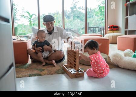 Porträt eines Großvaters mit seinem Enkel spielt in der Familienzimmer am Tag Stockfoto