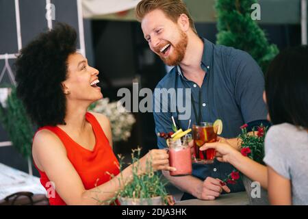 Freunde, die eine tolle Zeit im Café, lächeln und trinken Cocktails genießen zusammen. Stockfoto