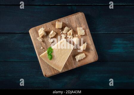 Zerbröckelter Parmesankäse, von oben auf dunkelblauem Holzhintergrund geschossen Stockfoto