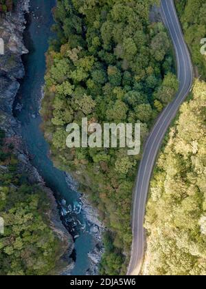 Straße und Bergfluss durch den grünen Wald, Luftbild Auto LKW-Fahrt durch den Wald, Luftbild Wald, Textur des Waldes Blick von oben her Stockfoto