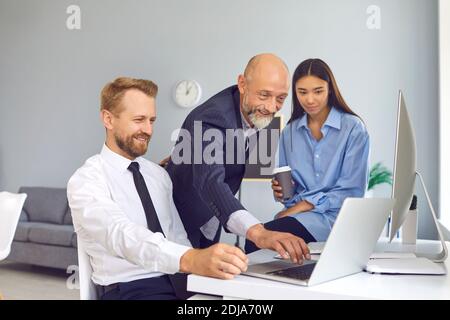 Glückliche Büromitarbeiter, die mit einem Laptop an einem Projekt arbeiten oder Um ein lustiges Video während der Pause zu sehen Stockfoto