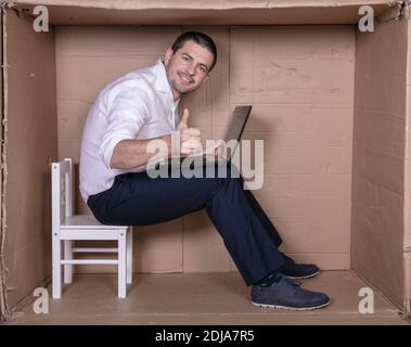 Geschäftsmann sitzt in seinem engen Büro zufrieden mit seiner Arbeit Stockfoto