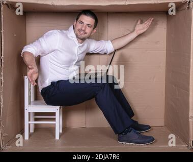 Geschäftsmann sitzt in seinem engen Büro zufrieden mit seiner Arbeit Stockfoto