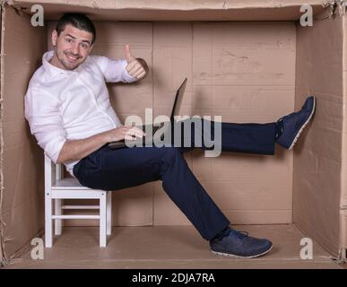 Geschäftsmann sitzt in seinem engen Büro zufrieden mit seiner Arbeit Stockfoto