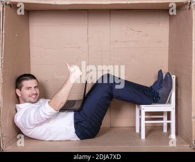 Geschäftsmann sitzt in seinem engen Büro zufrieden mit seiner Arbeit Stockfoto