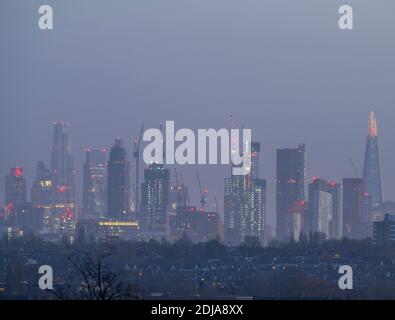 London, Großbritannien. 14 Dezember 2020. City of London Wolkenkratzer beleuchtet vor Sonnenaufgang mit weihnachtslichtern am Shard (rechts) und Tower 42, früher der NatWest Tower (links). Ein hoher Baukran (Mitte) ist ebenfalls mit mehrfarbigen festlichen Lichtern aufgereiht. Blick ist von einem Punkt 12km entfernt. Kredit: Malcolm Park/Alamy Stockfoto