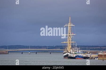 Der Pelican of London A Class A Tall Ship am Kai am Hafen von Montrose mit der Road und Rail Bridges im Hintergrund. Stockfoto