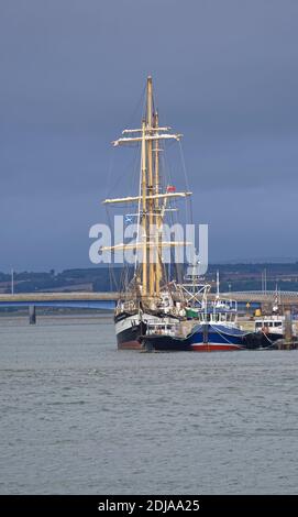 Der Pelican of London A Class A Tall Ship am Kai am Hafen von Montrose mit der Road und Rail Bridges im Hintergrund. Stockfoto