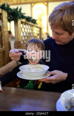 Großmutter füttert ihren Enkel in einem Restaurant Stockfoto