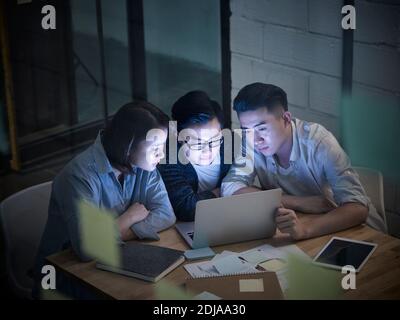 Drei junge asiatische Unternehmer arbeiten spät Treffen im Büro diskutieren Unternehmen mit Laptop-Computer Stockfoto