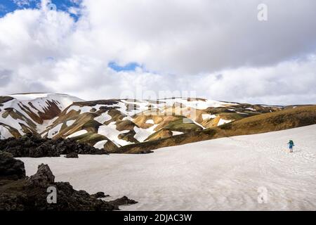 Ein Wanderer, der am ersten Tag der Laugavegur-Wanderung, Juni, Island, auf Schnee von Landmanaugar zu den Regenbogenbergen aufsteigt Stockfoto