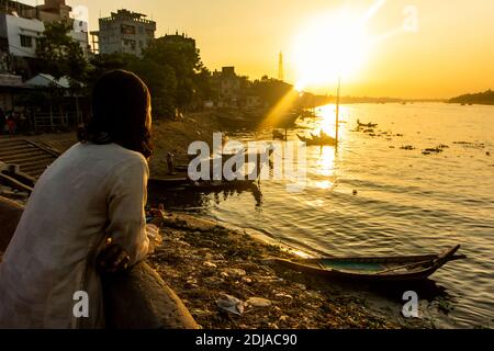 Dhaka, Bangladesch - Oktober 31: Ein Mann schaut auf den Buriganga Fluss bei Sonnenuntergang, mit auf dem Hintergrund einige Boote, die den Fluss in Dhaka überqueren während o Stockfoto