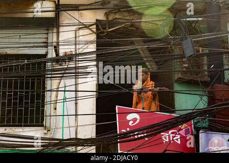 Dhaka, Bangladesch - 31. Oktober 2018: Eine Frau schaut von einem Balkon aus in die Stromkabel gestürzt auf die Straße. Stockfoto