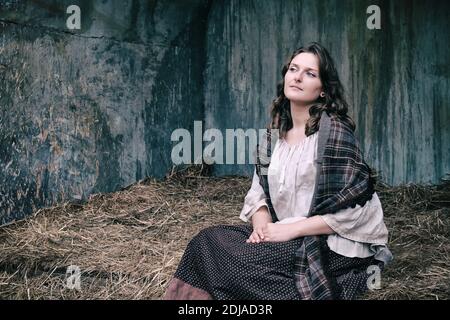 Porträt einer Frau in einer alten Scheune mit schäbigen Wänden, Nahaufnahme Stockfoto